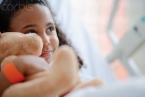 Little Girl with Teddy Bear in Hospital Bed